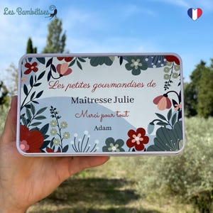 Peut inclure: Une boîte en métal blanc avec un motif floral et le texte "Les petites gourmandises de Maitresse Julie Merci pour tout Adam".