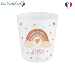 Puede incluir: Taza de cer&aacute;mica blanca con un dise&ntilde;o de arco&iacute;ris, nubes y corazones. El nombre "Laiia" est&aacute; escrito en cursiva debajo del arco&iacute;ris.