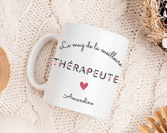 Puede incluir: Taza de cerámica blanca con texto negro que dice "Le mug de la meilleure THÉRAPEUTE" con un corazón rosa y el nombre "Amandine" debajo.