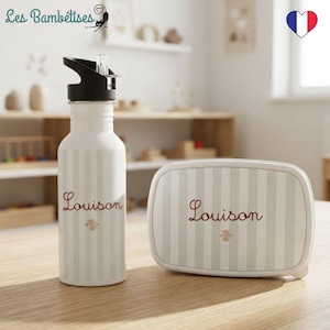 Peut inclure: Une gourde blanche avec un bouchon noir et une boîte à déjeuner rectangulaire assortie, toutes deux ornées de rayures verticales vert clair. Chaque article est personnalisé avec le prénom Louison en rouge et une petite icône d'oiseau.
