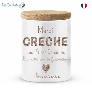 Op de afbeelding: Een witte keramische pot met een kurken deksel. De pot heeft de tekst "Merci CRECHE Les P'tites Canailles Pour cette année fantastique" in bruine letters, samen met een hart en de naam "Anastasia".