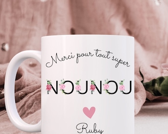 May include: White ceramic mug with a black floral design and the text "Merci pour tout super Nounou" with a pink heart and the name "Ruby" below.