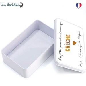 May include: A white rectangular tin box with a lid. The lid has text in French that says "Les petites gourmandises de ma super CR&Egrave;CHE" and "Merci de m'avoir aid&eacute; &agrave; grandir - Rapha&euml;l". A small brown heart is also on the lid.
