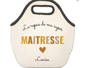 Puede incluir: Bolsa de almuerzo de color crema con asa y ribete gris oscuro. La bolsa presenta el texto "Le repas de ma super MAITRESSE" en letras negras y doradas, con un corazón dorado y el nombre "Louisa" debajo. La bolsa tiene un borde cosido.