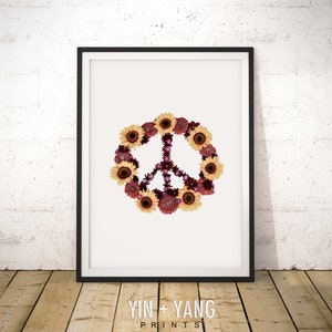 May include: A peace sign made of yellow sunflowers and burgundy flowers on a white background. The image is framed in black.