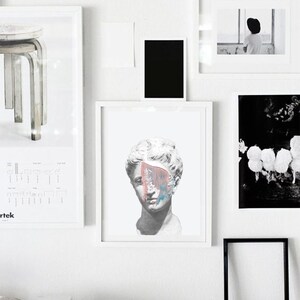 May include: A white framed print of a plaster bust of a woman with a colorful abstract paint splatter across her face.
