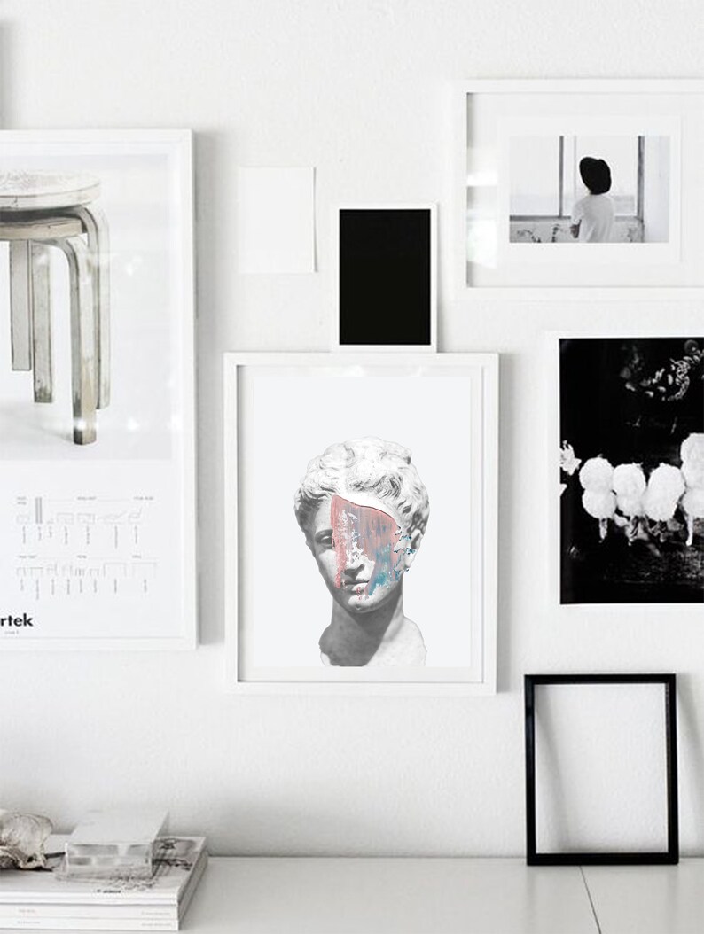 May include: A white framed print of a plaster bust of a woman with a colorful abstract paint splatter across her face.