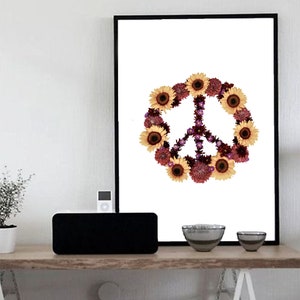 May include: A framed print of a peace sign made of sunflowers and purple flowers on a white background.