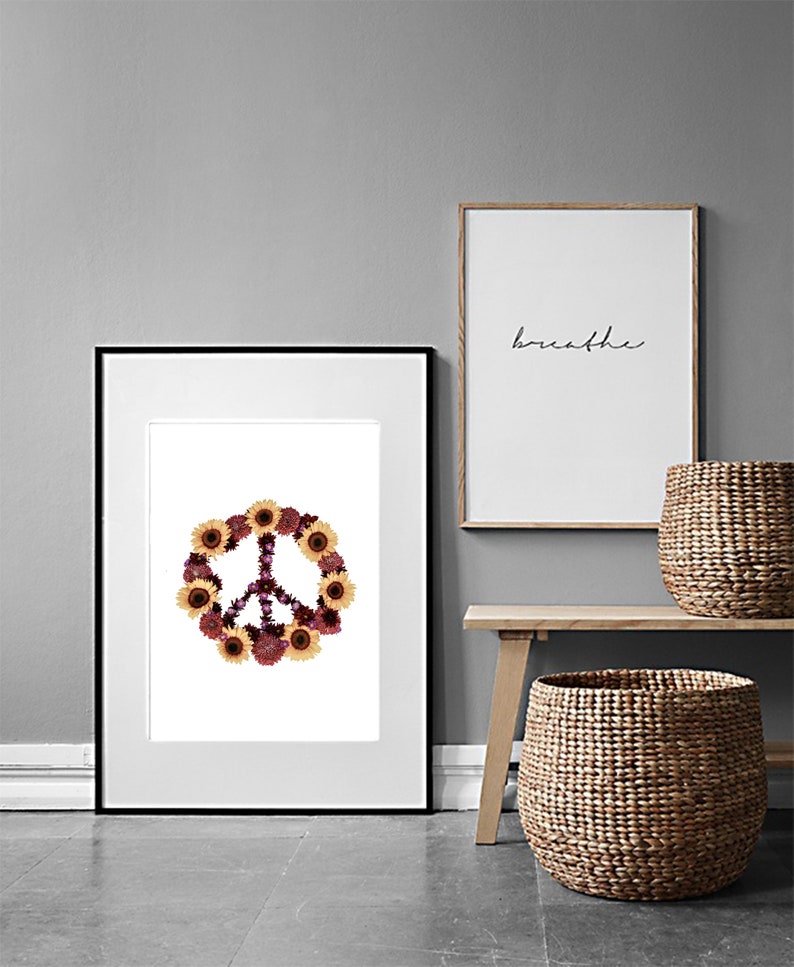 May include: A framed print of a peace sign made of dried flowers, including sunflowers and purple flowers. The print is hanging on a gray wall next to a framed print with the word "breathe" written in black ink.