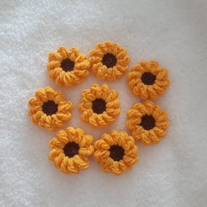 Può includere: Otto decorazioni a forma di girasole all'uncinetto di colore giallo con centri marroni.