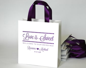 20 welkomsttassen voor bruiloften met handgrepen van paars satijnen lint en uw namen - Love is sweet bags voor uw gasten - Bruiloftsgeschenken en gunsten.