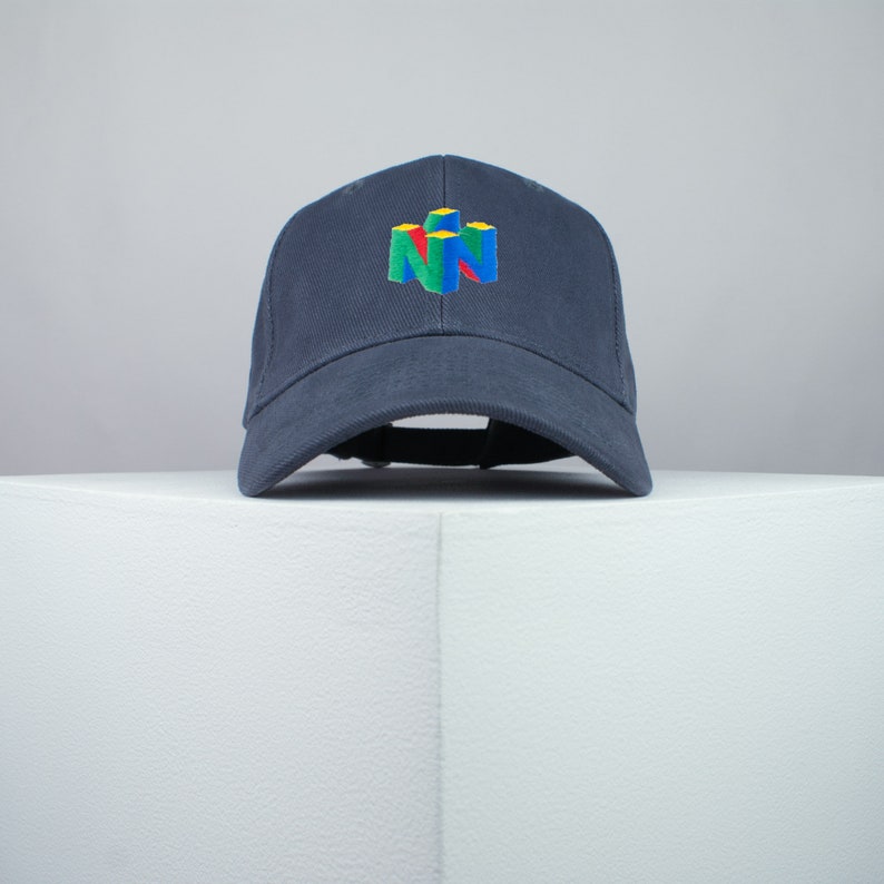 May include: A dark blue baseball cap with a white, red, green, and yellow Nintendo logo embroidered on the front.