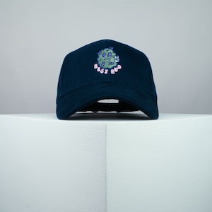 May include: A dark blue baseball cap with an embroidered green cartoon weed character and the text "Best Bud".