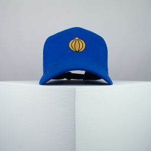 May include: A royal blue baseball cap with a yellow embroidered onion on the front.