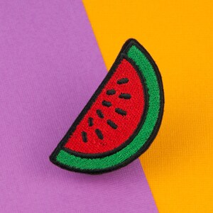 May include: A red and green watermelon patch, a felt applique, on a purple and orange background.