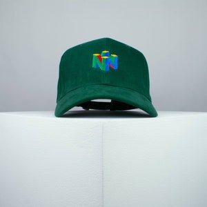 May include: A green baseball cap with a multi-colored Nintendo logo embroidered on the front.