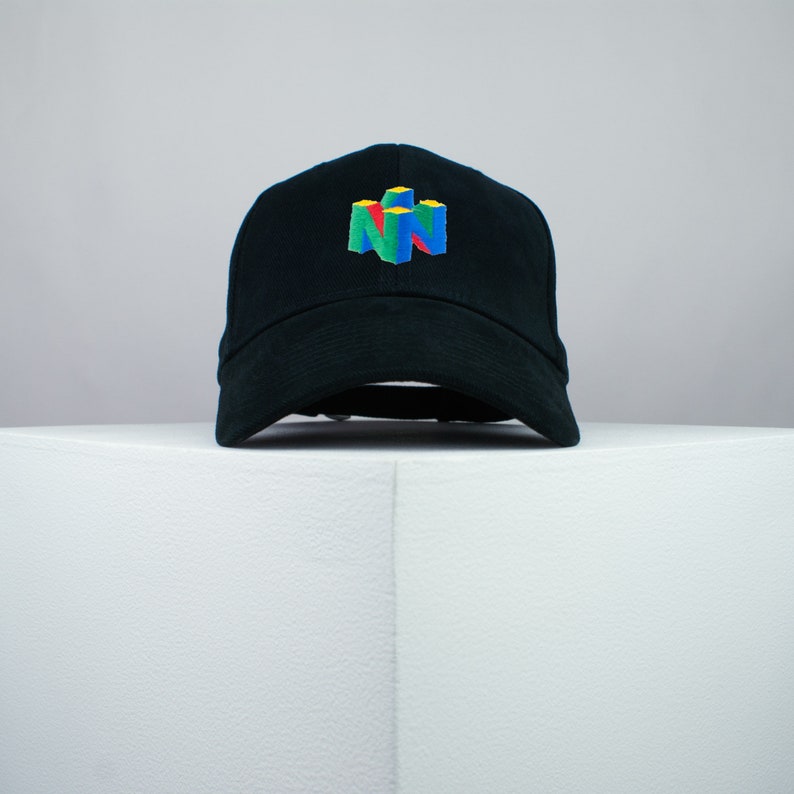 May include: A black baseball cap with a colorful Nintendo 64 logo embroidered on the front.