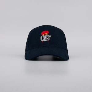 May include: A navy blue baseball cap with a curved brim. The cap features an embroidered design of a red chef's hat and a gaming console with the text "GAMING IS MY THERAPY".