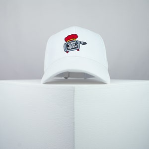 May include: White baseball cap with an embroidered image of a toaster with the text "Gaming is my therapy".