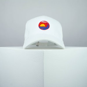 May include: White baseball cap with an embroidered sun and wave design in red, yellow and blue.