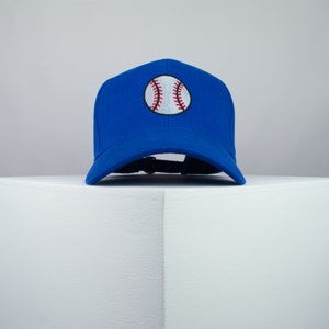 May include: A royal blue baseball cap with a white baseball stitched on the front.