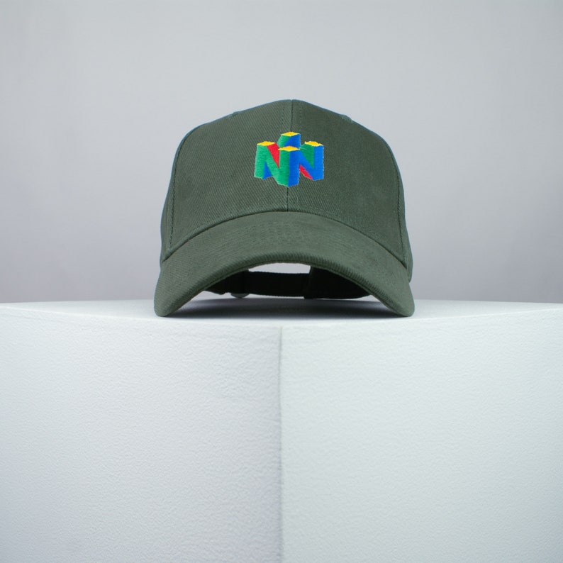 May include: A dark green baseball cap with an embroidered Nintendo 64 logo in yellow, blue, red, and green.