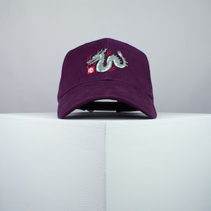 May include: A purple baseball cap with an embroidered green dragon and red Chinese character.