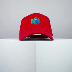May include: A red baseball cap with a colorful Nintendo logo embroidered on the front.