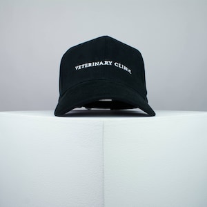 May include: A black baseball cap with white embroidery that reads "VETERINARY CLINIC".