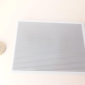 Puede incluir: Una tarjeta rectangular blanca con l&iacute;neas negras paralelas espaciadas uniformemente. A la izquierda de la tarjeta hay una moneda plateada con caracteres japoneses. El fondo es de color rosa claro.