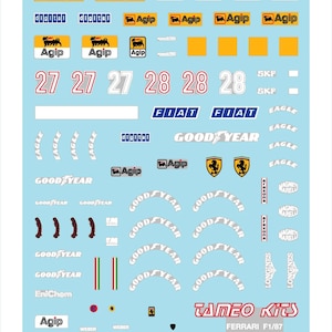 Puede incluir: Una hoja de calcomanías para modelos de coches con logotipos de Agip, Goodyear, Fiat y otras marcas. Incluye los números de carrera 27 y 28, y el texto "TAMEO Kits" y "FERRARI F1/87". Las calcomanías están sobre un fondo azul claro.