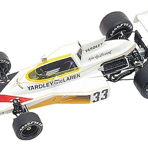 May include: A white and gold Yardley McLaren race car model with the number 33. The car has black tires with "Goodyear" branding and a rear wing with "Yardley" and "Goodyear" text.