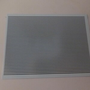 Puede incluir: Una hoja rectangular con un fondo azul claro y l&iacute;neas horizontales negras espaciadas uniformemente. Las l&iacute;neas crean un patr&oacute;n de rayas. La hoja se coloca sobre un fondo liso blanquecino. Las l&iacute;neas son paralelas.