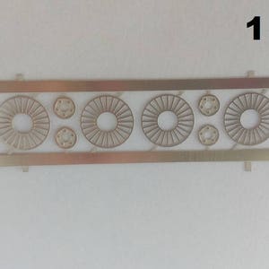 Puede incluir: Una lámina de metal dorado con recortes de círculos y hexágonos. La lámina está etiquetada con "1 set".