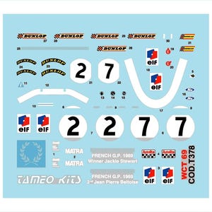 Può includere: Un foglio di decalcomanie per auto da corsa con cerchi bianchi numerati 2 e 7, e loghi "DUNLOP" e "elf". Il testo include "FRENCH G.P. 1969" e il marchio "MATRA". Lo sfondo è azzurro.