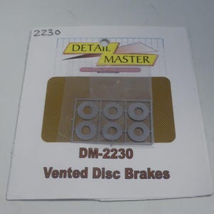 May include: Detail Master DM-2230 Vented Disc Brakes model kit. The package features a clear plastic sheet containing six gray, circular disc brake components. The Detail Master logo is visible at the top.