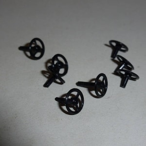 May include: Ten black plastic toy steering wheels with a small metal pin on the back.