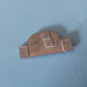 Könnte beinhalten: Ein silbernes Metallmodell eines Gebäudes mit zwei Fenstern. Das Modell hat ein abgerundetes Dach und eine flache Basis.