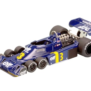 May include: A detailed model of a blue and yellow Formula 1 race car. The car features the number 3, Goodyear tyres, and Elf branding. The rear wing displays the Goodyear and Elf logos. The model has six wheels.
