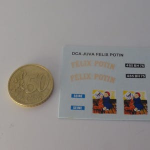 May include: A gold 50 Euro cent coin next to a small card with text and illustrations. The card includes the text "DCA JUVA FELIX POTIN", "FELIX POTIN", and "SEINE". There are also two illustrations of a child.