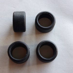 May include: Four black rubber tires for a toy car. The tires are round and have a smooth surface.