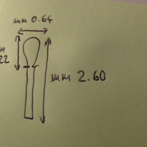 May include: A hand-drawn sketch on a light green square paper showing a vertical object with a rounded top and a straight stem. The drawing includes measurements of 0.64 mm for the width, 1.22 mm for the top section, and 2.60 mm for the total length.
