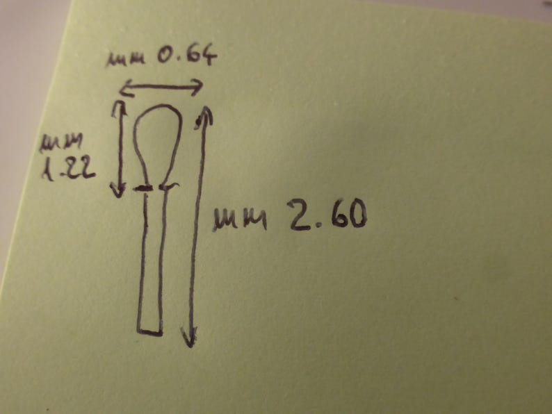 May include: A hand-drawn sketch on a light green square paper showing a vertical object with a rounded top and a straight stem. The drawing includes measurements of 0.64 mm for the width, 1.22 mm for the top section, and 2.60 mm for the total length.