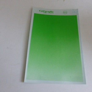 May include: A green sheet of paper with the word "Calligraphie" printed in black at the top.
