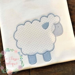 May include: White t-shirt with a blue and white applique of a sheep. The sheep has a gingham pattern on its legs and a blue face.
