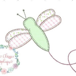 May include: A green and pink embroidered dragonfly with a long tail, with the text "The Classic Applique" in a floral wreath.