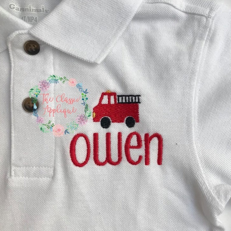 May include: White polo shirt with red embroidered fire truck and the name "owen" underneath.