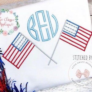 May include: White embroidered shirt with a blue monogram, two red, white, and blue American flags, and the text "Stitched by Lexie Grace Designs Embroidery Boutique".