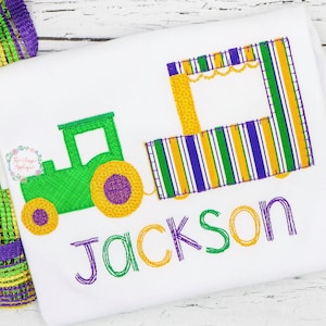 May include: Green and yellow embroidered tractor pulling a striped float with a purple, green, and yellow awning. The name Jackson is embroidered below the tractor and float.