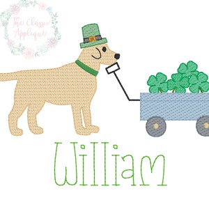 May include: An embroidered design featuring a tan Labrador Retriever wearing a green hat and collar, pulling a blue wagon filled with green shamrocks. The name "William" is written in green script below the dog.